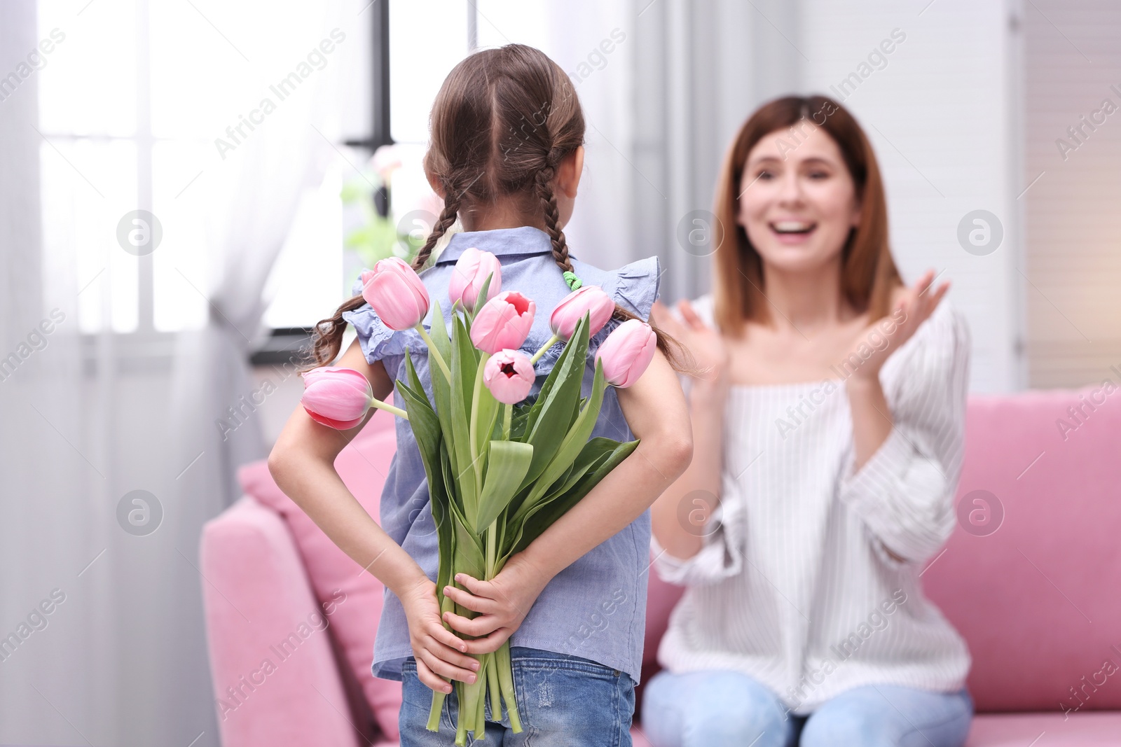 Photo of Happy mother and daughter with flowers at home. International Women's Day