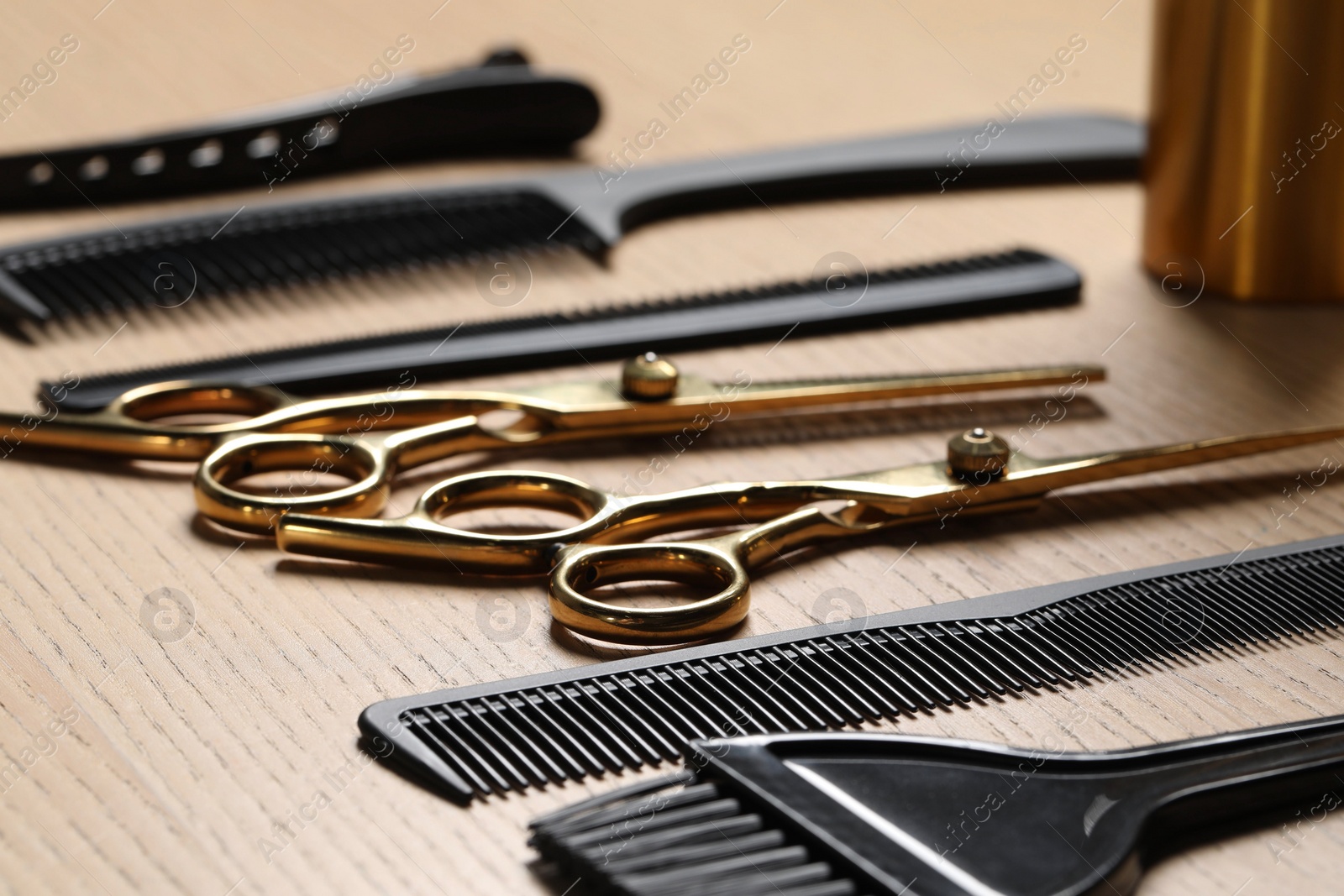 Photo of Hairdresser tools. Different scissors and combs on wooden table in salon, closeup
