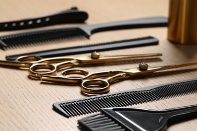 Photo of Hairdresser tools. Different scissors and combs on wooden table in salon, closeup