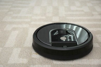 Modern robotic vacuum cleaner on light carpet