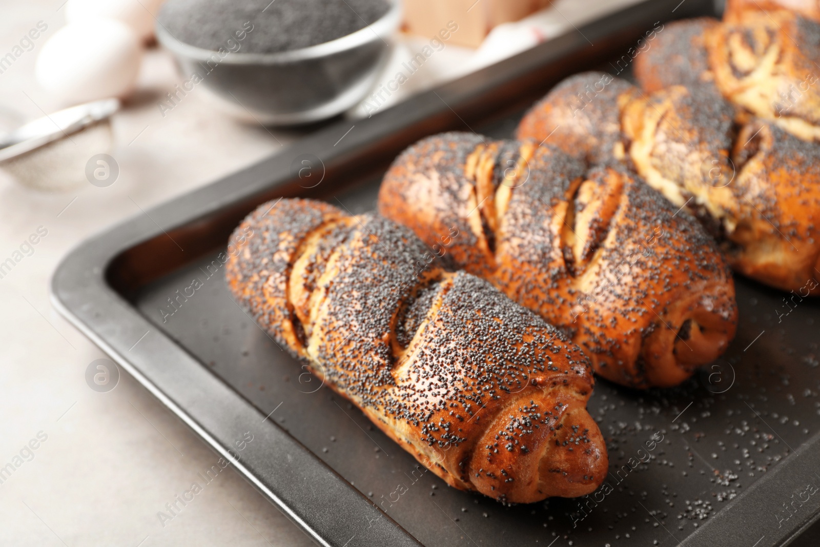 Photo of Baking tray with tasty poppy seed rolls  on table