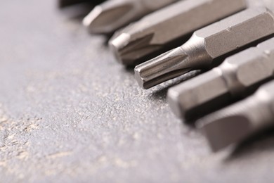 Different screwdriver bits on grey table, closeup