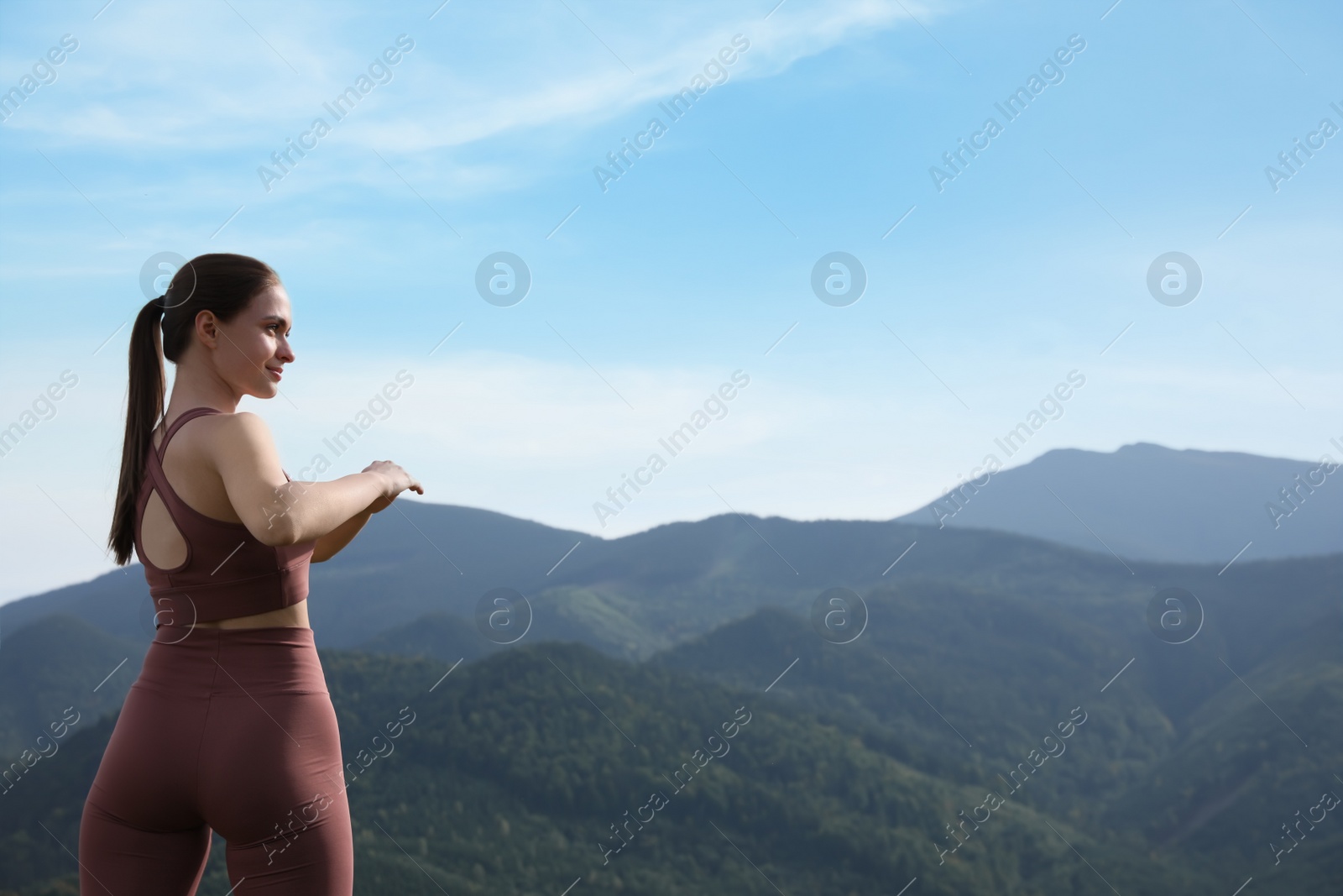 Photo of Young woman doing morning exercise in mountains, space for text