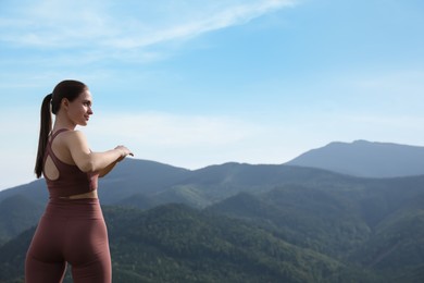 Young woman doing morning exercise in mountains, space for text