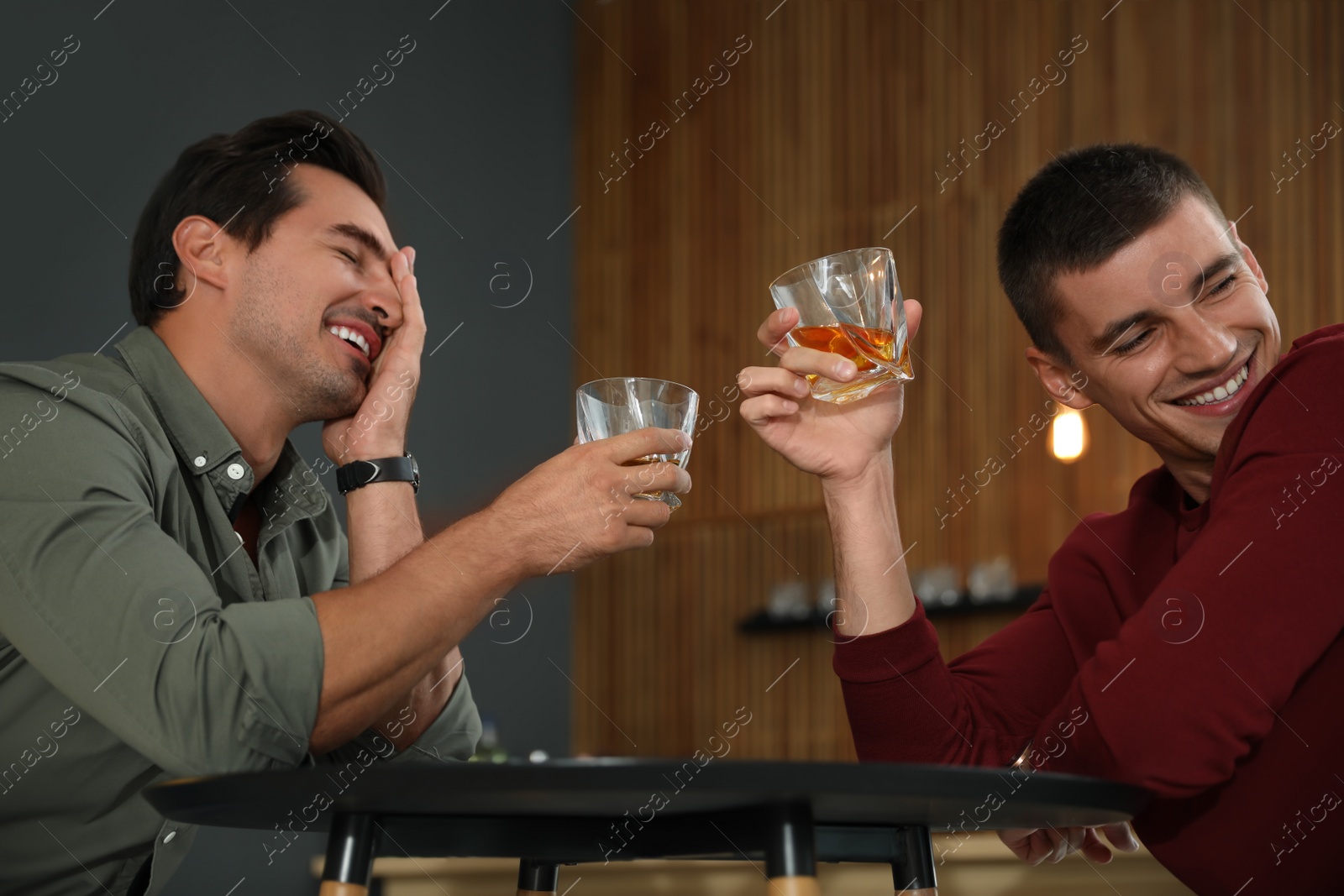 Photo of Young men drinking whiskey together in bar