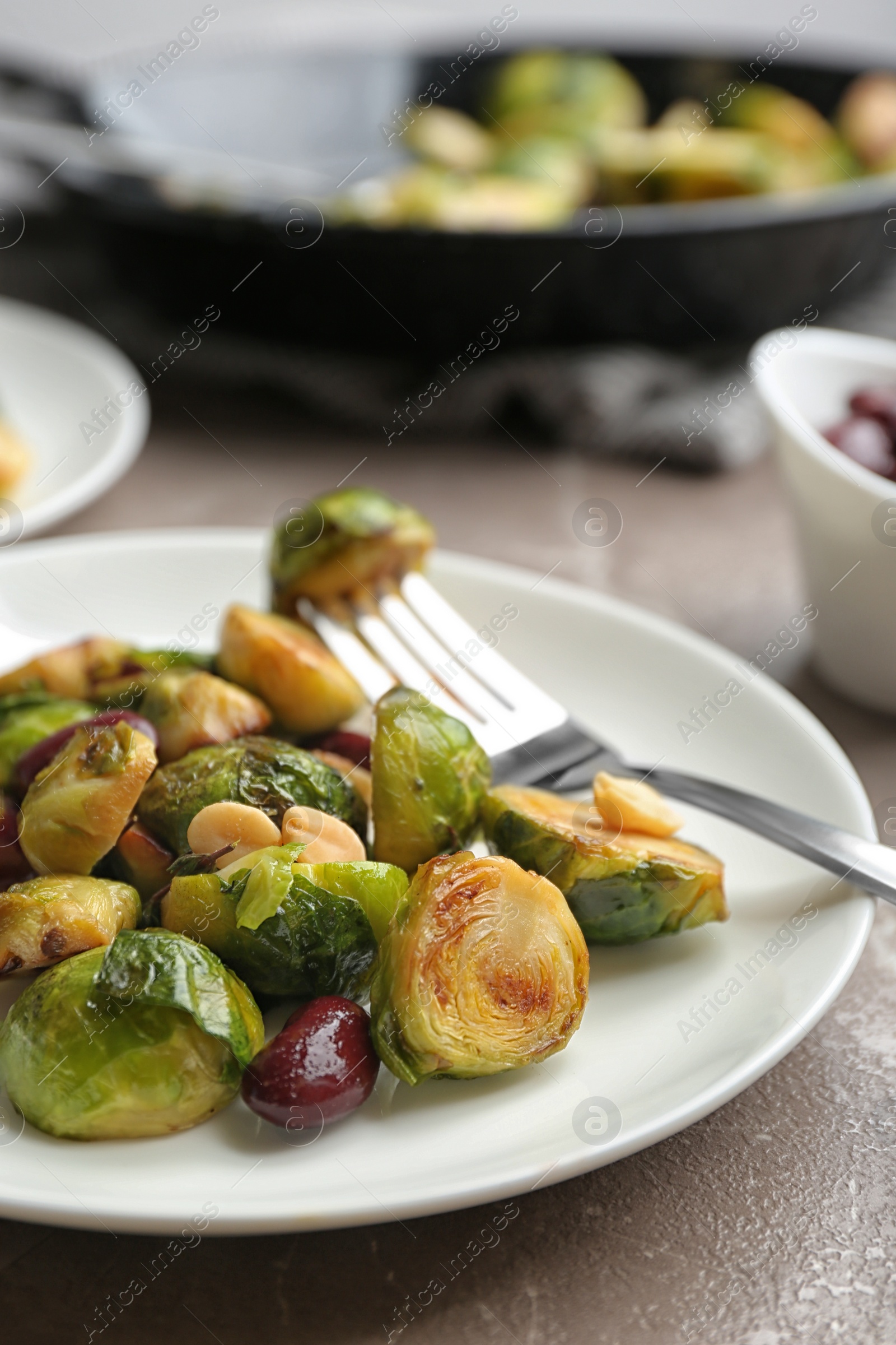 Photo of Delicious roasted brussels sprouts with red beans and peanuts served on grey marble table