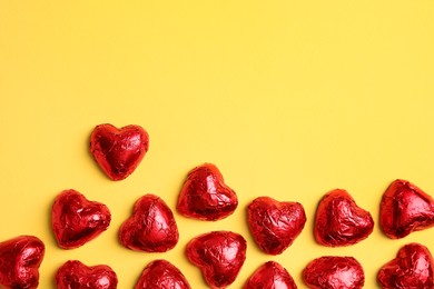 Photo of Heart shaped chocolate candies on yellow background, flat lay with space for text. Valentine's day treat