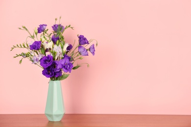 Photo of Beautiful bouquet of eustoma and freesia flowers in vase on color background. Space for text