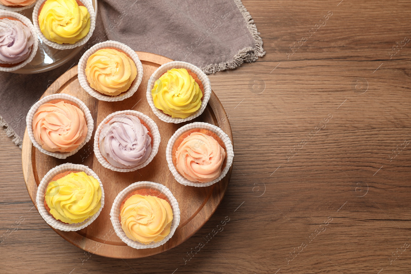 Photo of Stand with tasty cupcakes on wooden table, flat lay. Space for text