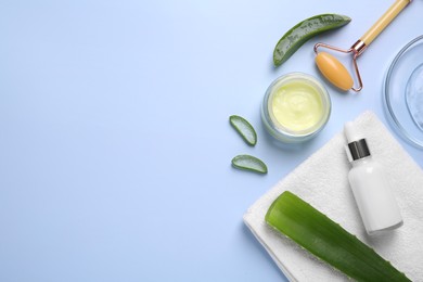 Flat lay composition with cosmetic products and cut aloe leaves on light blue background. Space for text