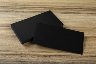 Blank black business cards on wooden background. Mockup for design