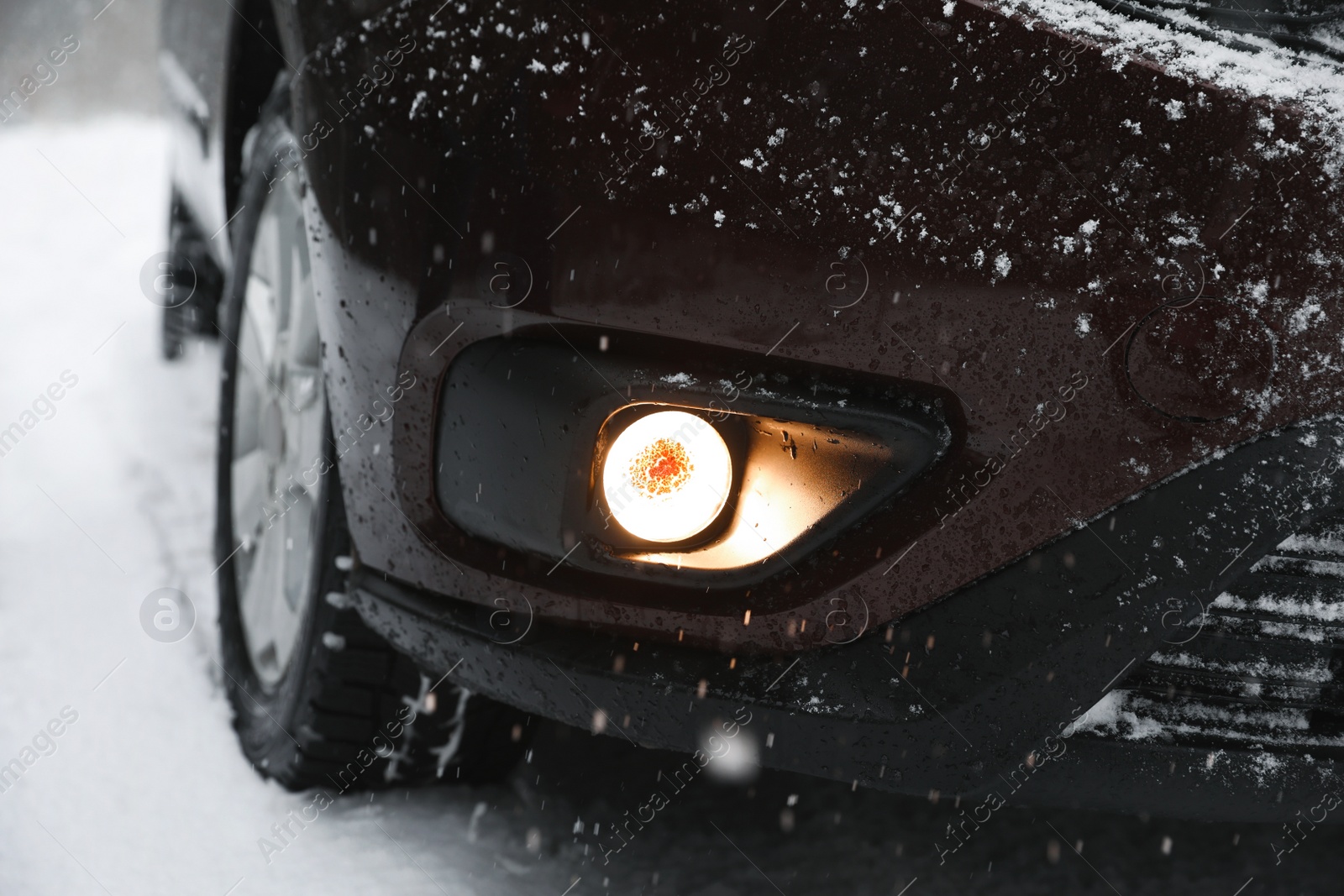 Photo of Closeup view of car on snowy road. Winter care