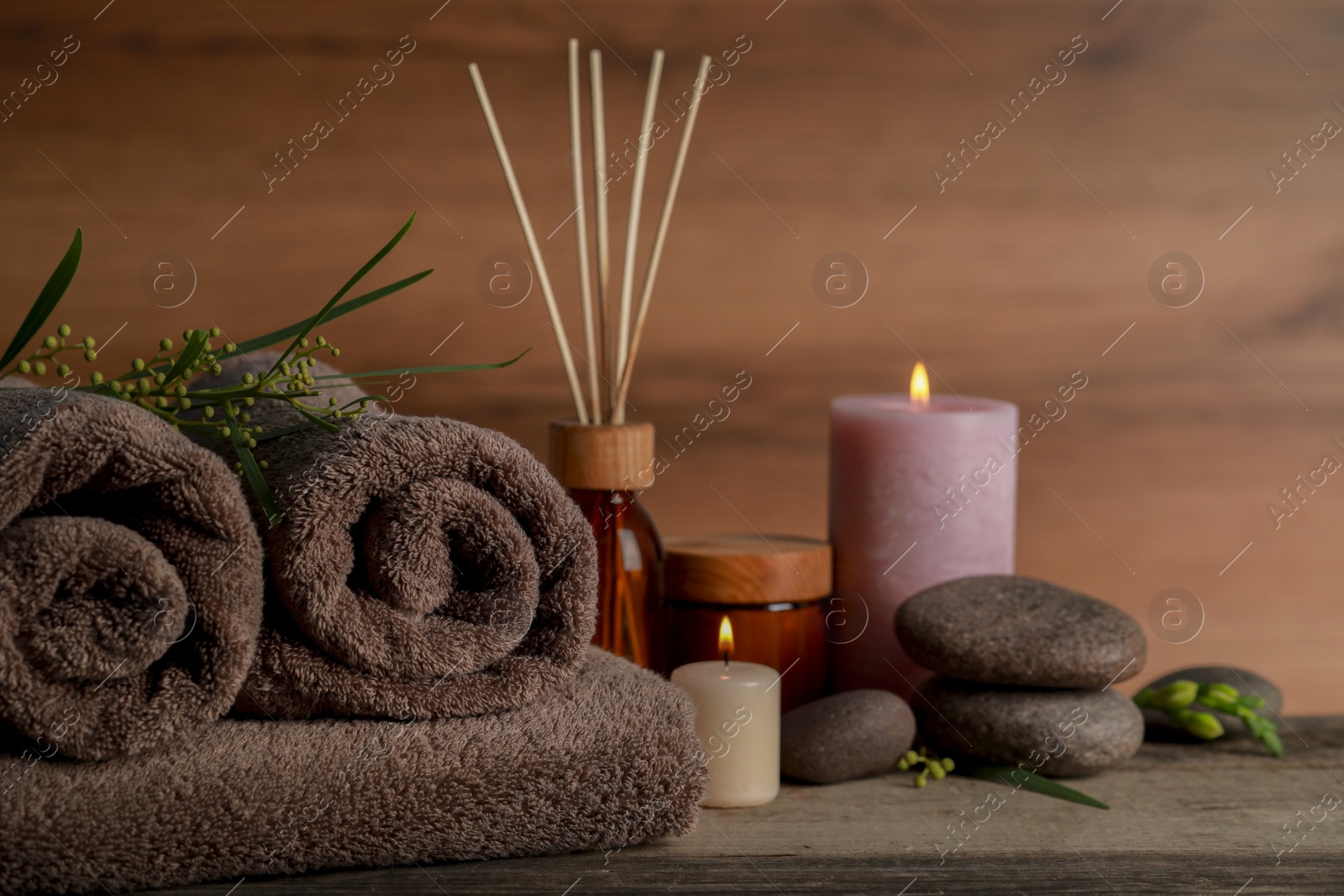 Photo of Beautiful spa composition with different care products and burning candles on wooden table