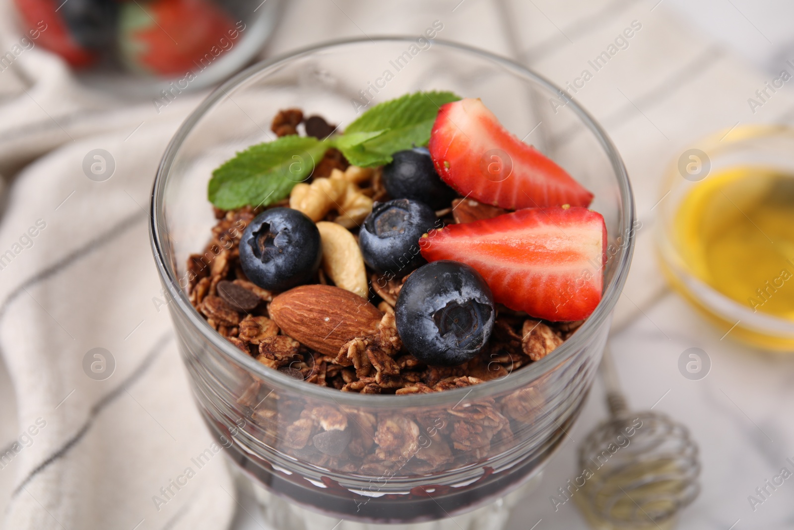 Photo of Tasty granola with berries and nuts in glass on table, closeup