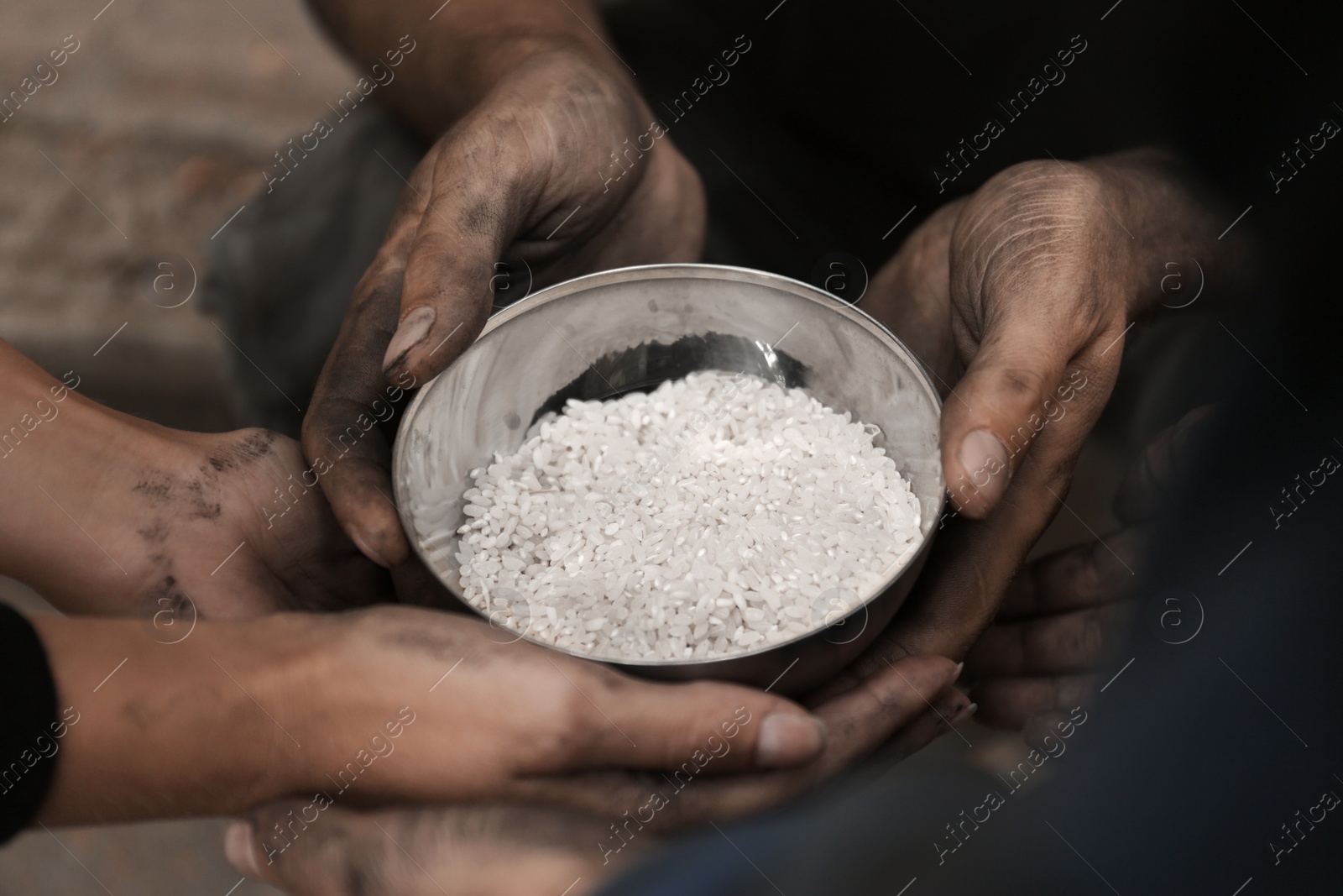 Photo of Poor homeless people with bowl of rice outdoors, closeup