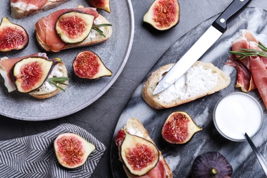 Photo of Sandwiches with ripe figs, cream cheese and prosciutto served on black table, flat lay
