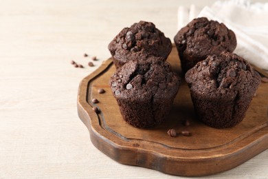 Delicious chocolate muffins on white wooden table, space for text