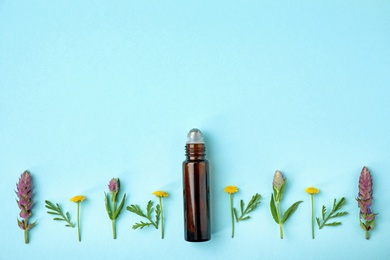 Bottle of essential oil and wildflowers on color background, flat lay. Space for text