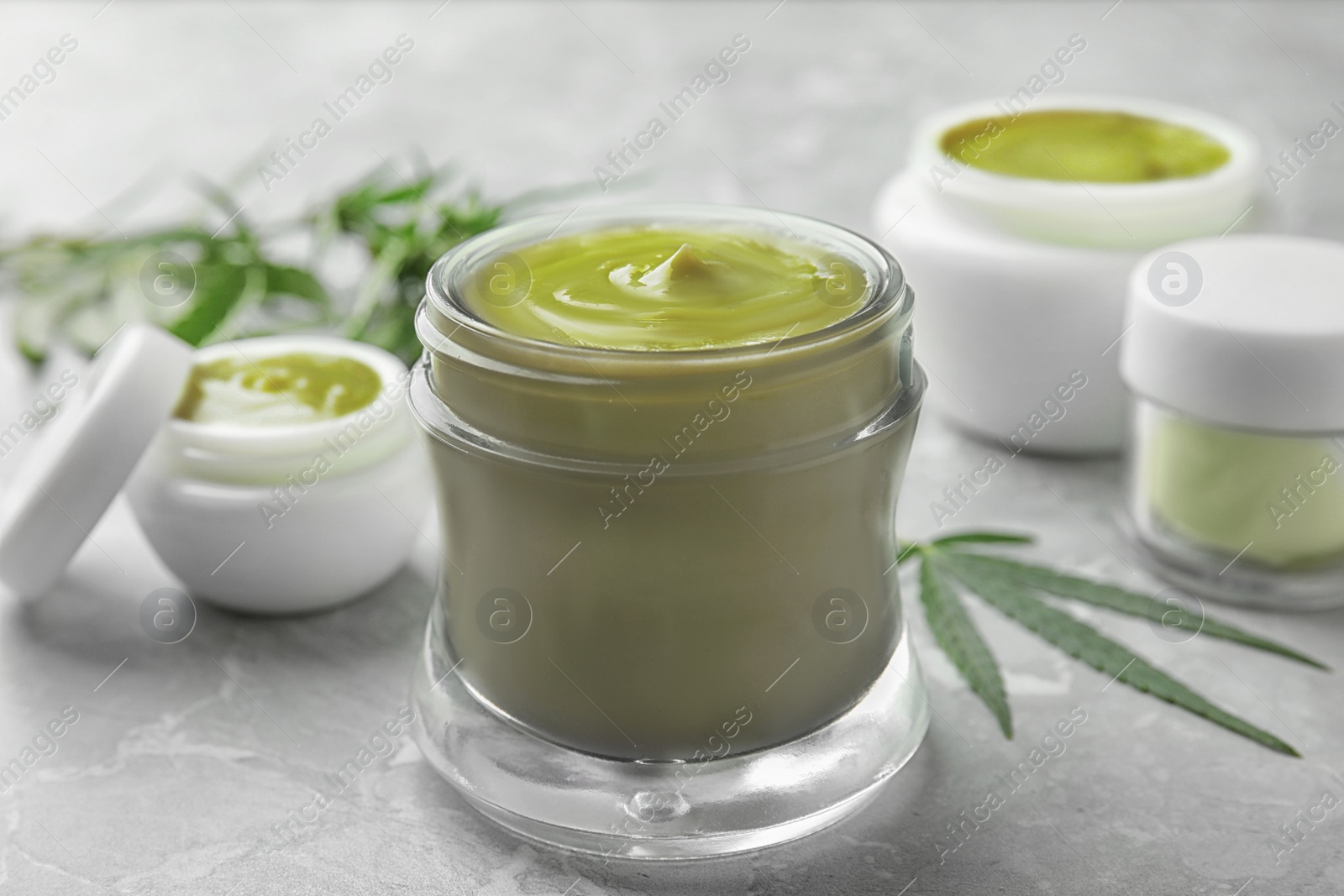 Photo of Jars of hemp cream on grey table, closeup. Organic cosmetics