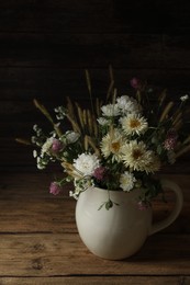 Photo of Bouquet of beautiful wild flowers and spikelets on wooden table