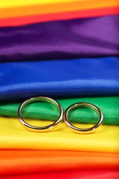 Wedding rings on rainbow LGBT flag, closeup