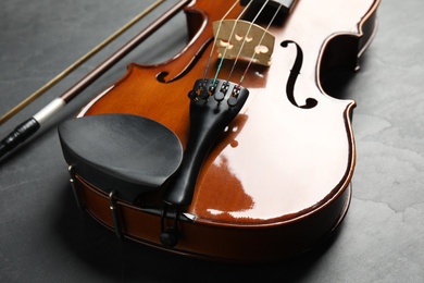 Photo of Classic violin and bow on grey stone background, closeup