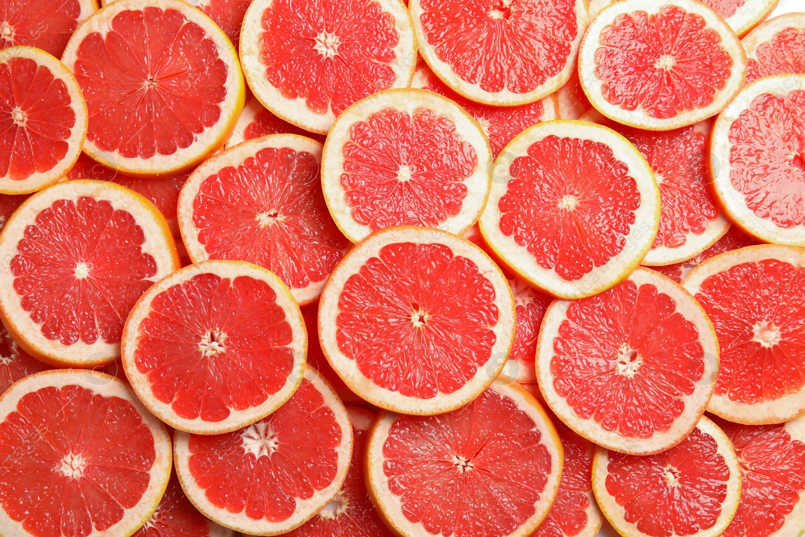 Photo of Many sliced fresh grapefruits as background, top view