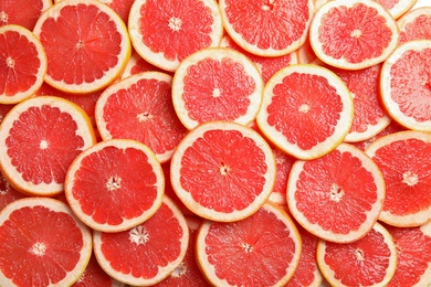 Many sliced fresh grapefruits as background, top view