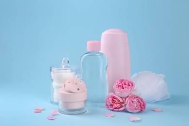 Different skin care products for baby, flowers and pacifier on light blue background. Space for text