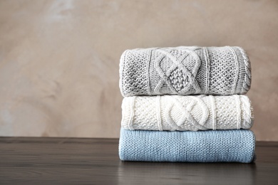 Photo of Stack of folded knitted sweaters on table. Space for text