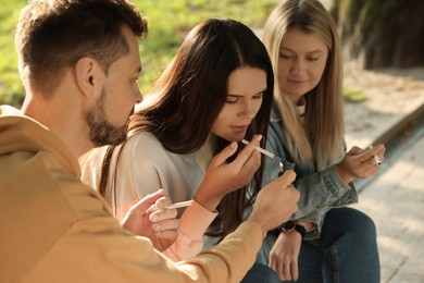 People smoking cigarettes outdoors on sunny day