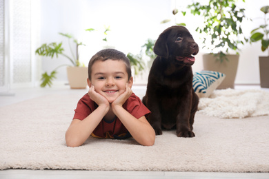 Photo of Little boy with puppy on floor at home. Friendly dog