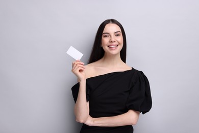 Photo of Happy woman holding blank business card on light grey background