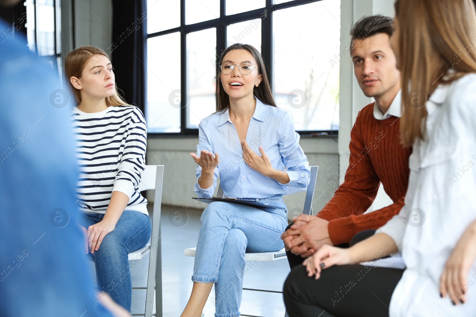 Photo of Psychotherapist working with patients in group therapy session indoors