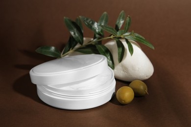 Photo of Jar of natural cream, stone and olives on brown background. Cosmetic products
