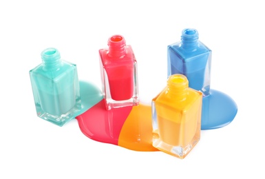 Spilled different nail polishes with bottles on white background