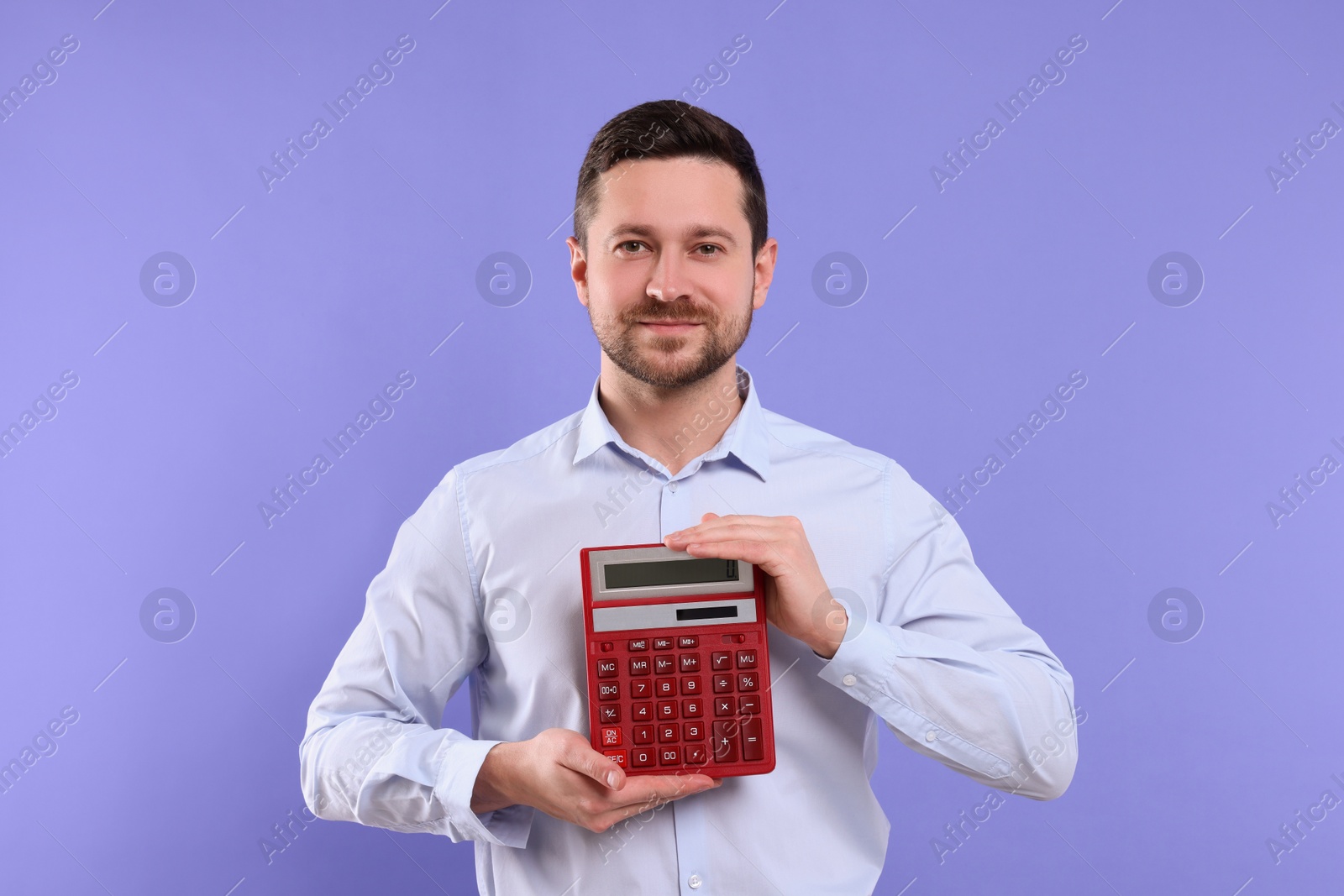 Photo of Happy accountant showing calculator on violet background