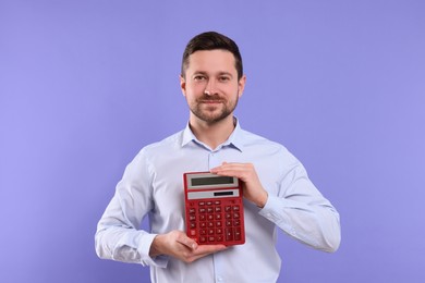 Photo of Happy accountant showing calculator on violet background