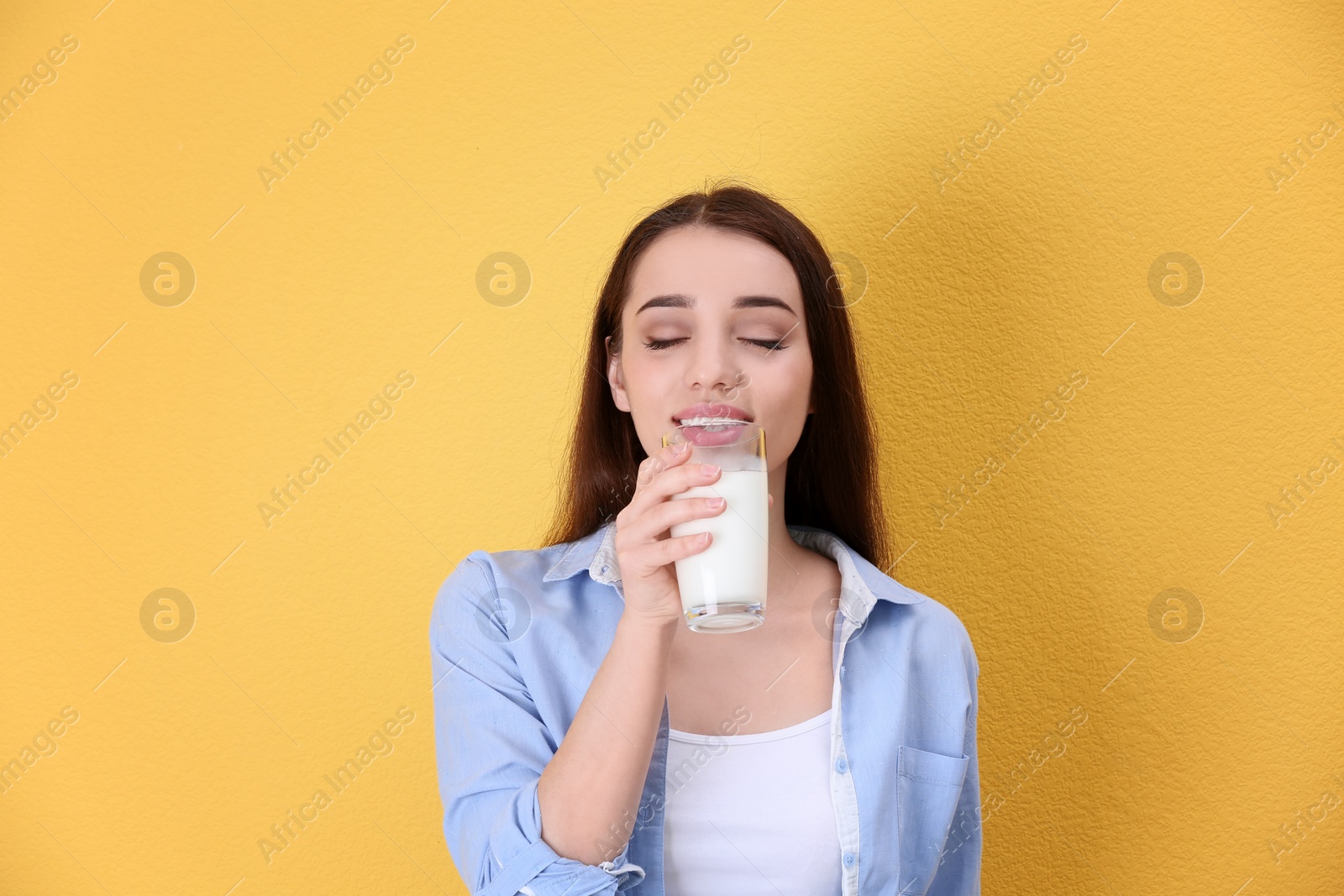 Photo of Beautiful young woman drinking milk on color background