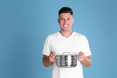 Happy man with pot on light blue background
