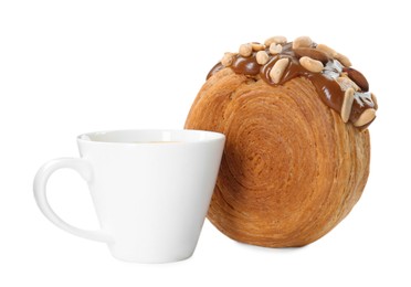 Photo of Round croissant with chocolate paste, nuts and cup of drink isolated on white. Tasty puff pastry