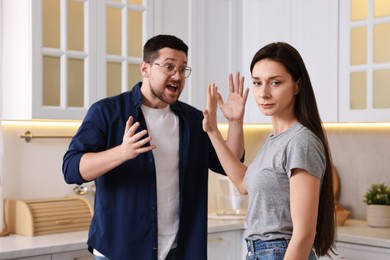 Photo of Wife stopping her screaming husband in kitchen. Relationship problems