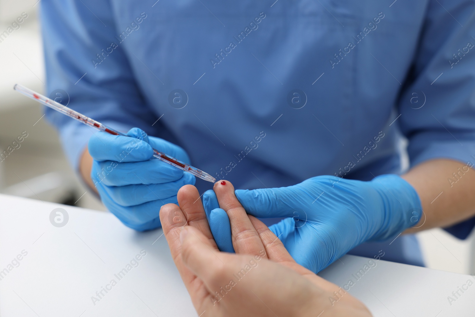 Photo of Laboratory testing. Doctor taking blood sample from patient at white table in hospital, closeup