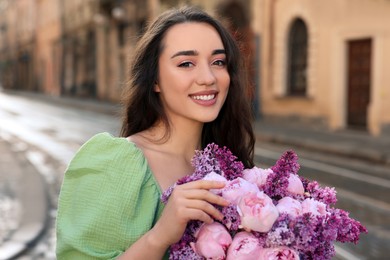 Photo of Beautiful woman with bouquet of spring flowers on city street