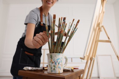 Photo of Woman taking brush from mug in studio, closeup