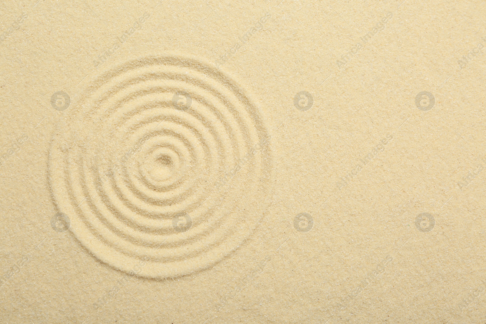 Photo of Zen rock garden. Circle pattern on beige sand, top view