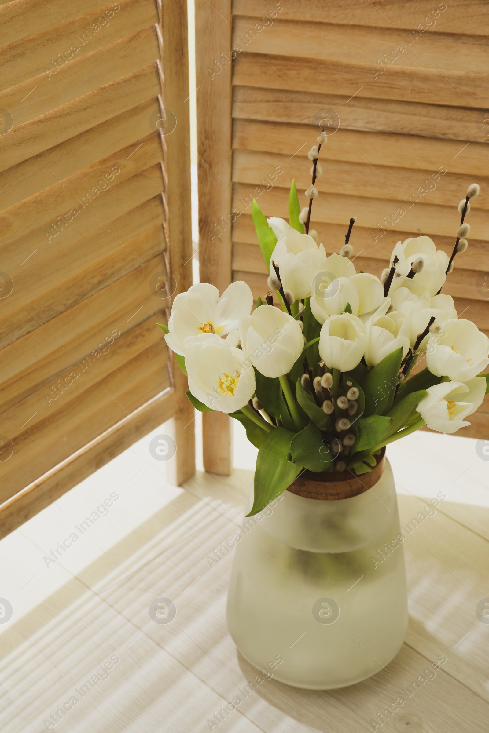 Photo of Beautiful bouquet of willow branches and tulips in vase indoors