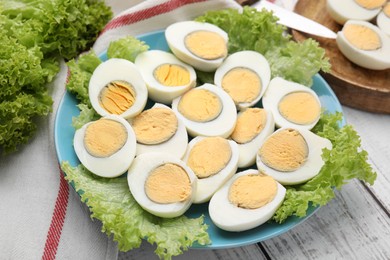 Photo of Fresh hard boiled eggs and lettuce on white wooden table