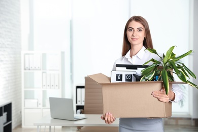 Photo of Happy young woman holding box with stuff at office