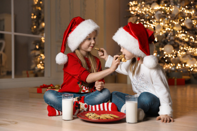 Photo of Cute little children eating cookies in living room. Christmas time